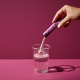 noola Energy Drink Stick Wildbeere wird in ein Glas Wasser eingerührt