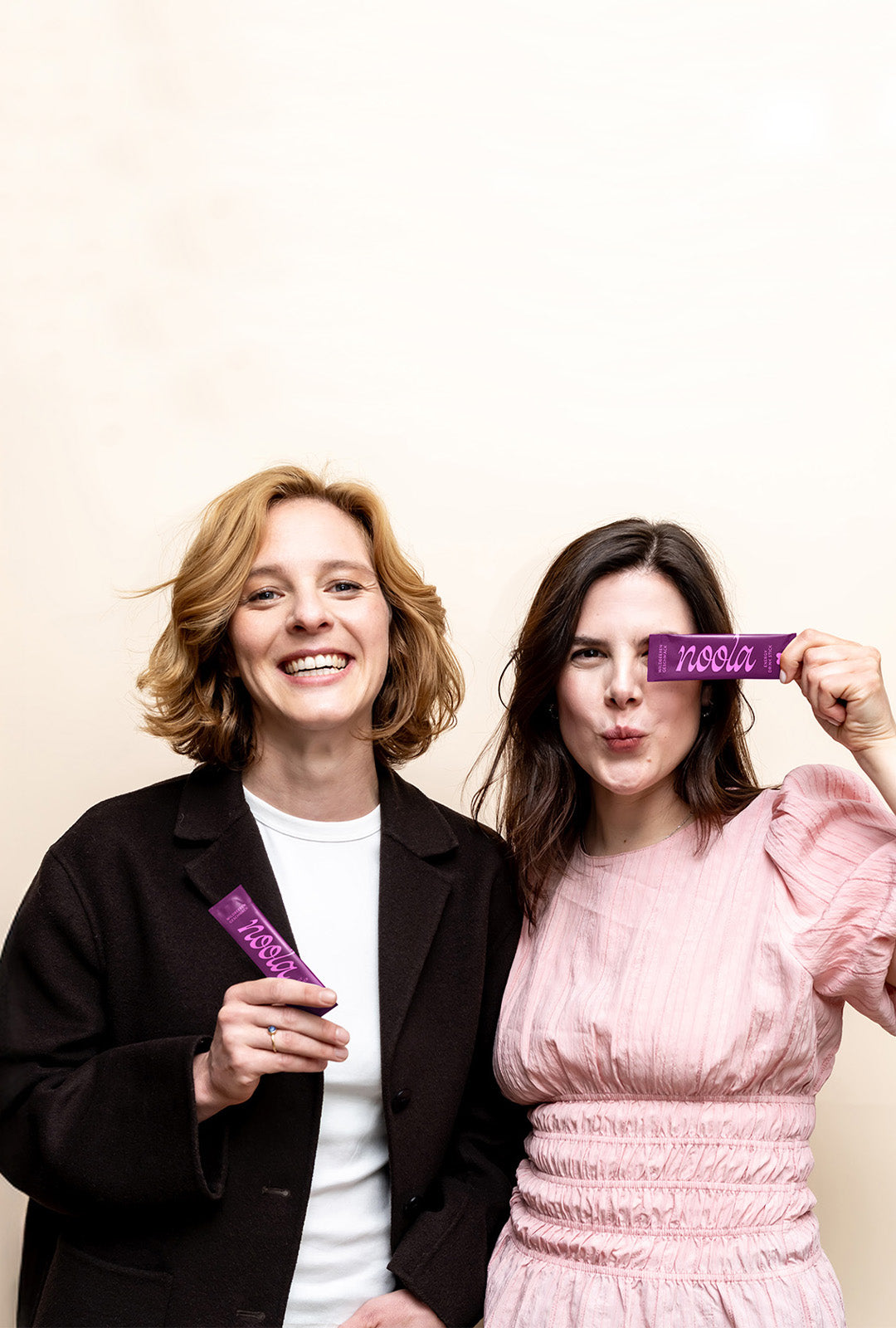 Zwei Frauen lachen und halten noola Energy Pulver Sticks in der Hand