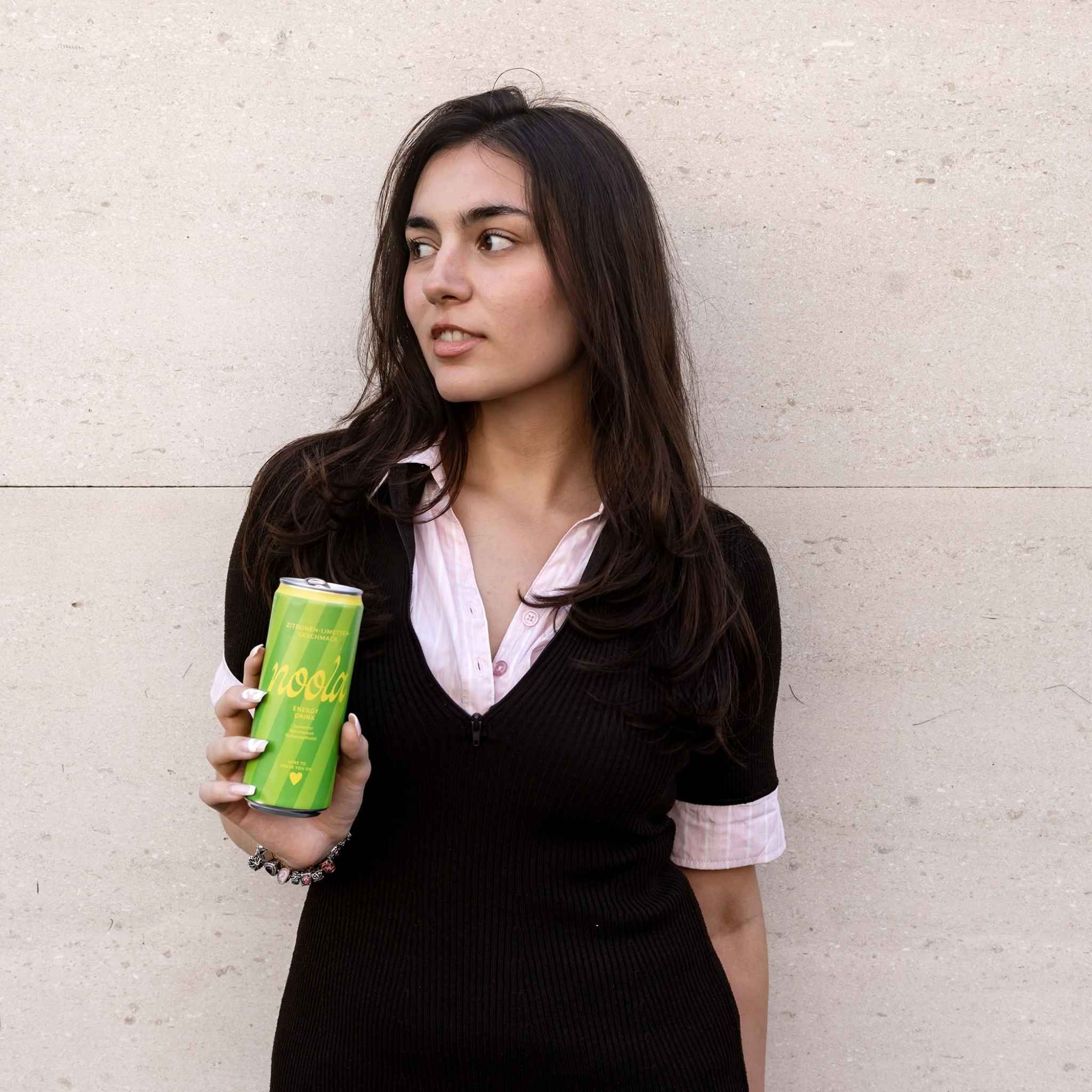 Frau hält noola Energy Dose Zitrone-Limette in der Hand
